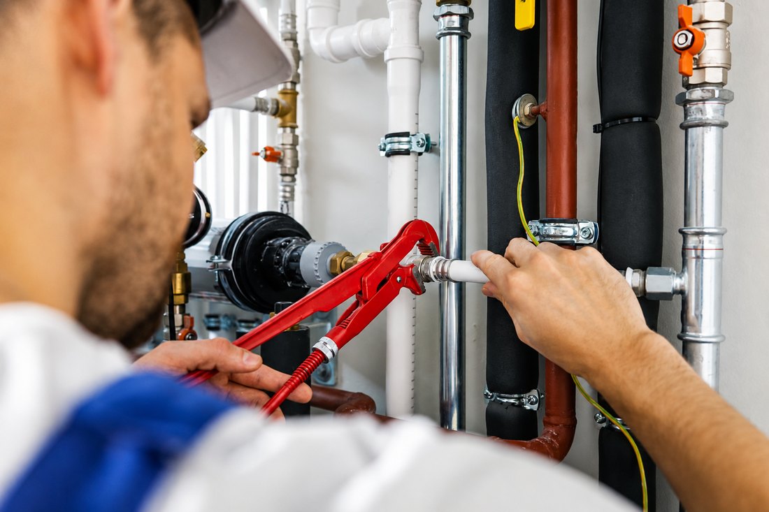 Plumber fitting a radiator valve with a pipe wrench
